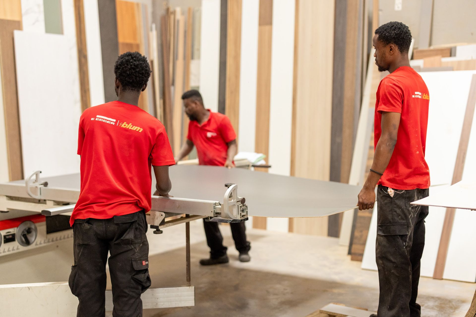 Three technicians carrying a board through the board store